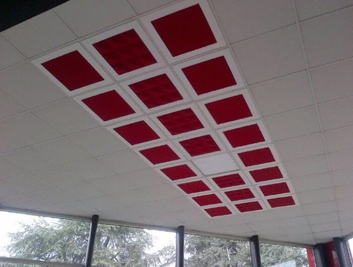 Acoustic Panels Uniko Flat and Uniko Piramid panels in red shown ceiling mounted