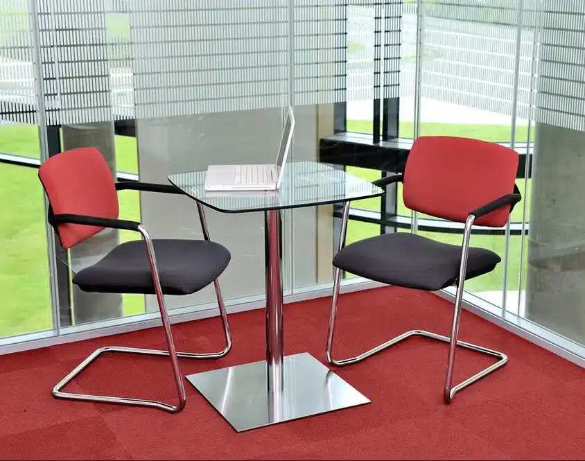 Alina Chair two armchairs with upholstered seats and inner backs, plastic outer backs and chrome cantilever frames shown by a round table