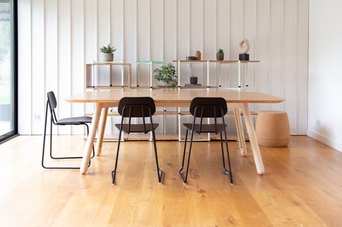 Blume Table with a sawn edge top shown in an office with three black Swing chairs