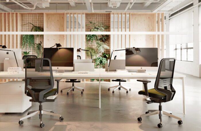 Dot.Pro Task Chair four chairs with 4D adjustable arms, lumbar support and silver bases shown around a bench desk in an office