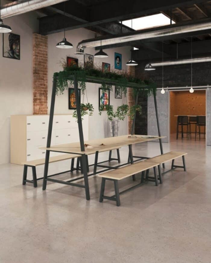 Equus Tables dining height table with overhead frame and planter grids, shown with plants and four bench seats in a breakout space