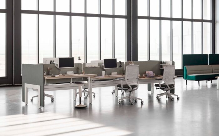 Evolve2 Chair five task chairs with white bases, white membrane backs and upholstered seats shown by a bench desk in a work space
