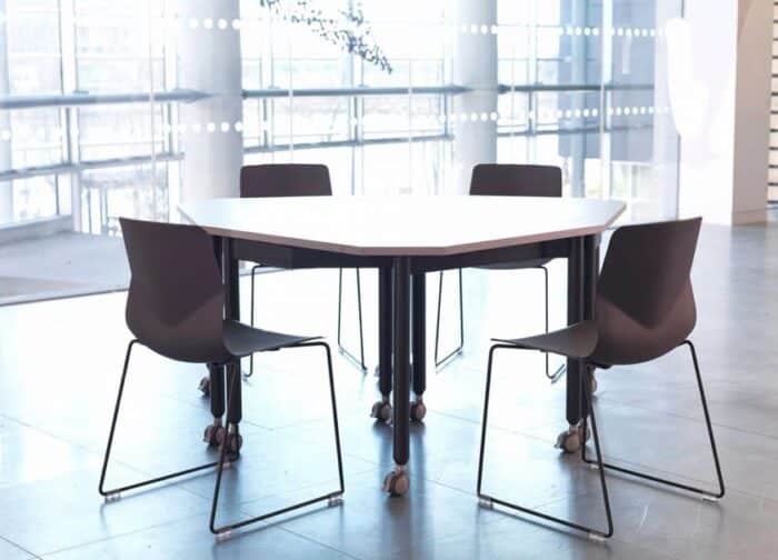 FourKonnect Tables triangular shape configuration with black straight legs on castors, shown in a workplace with two chairs