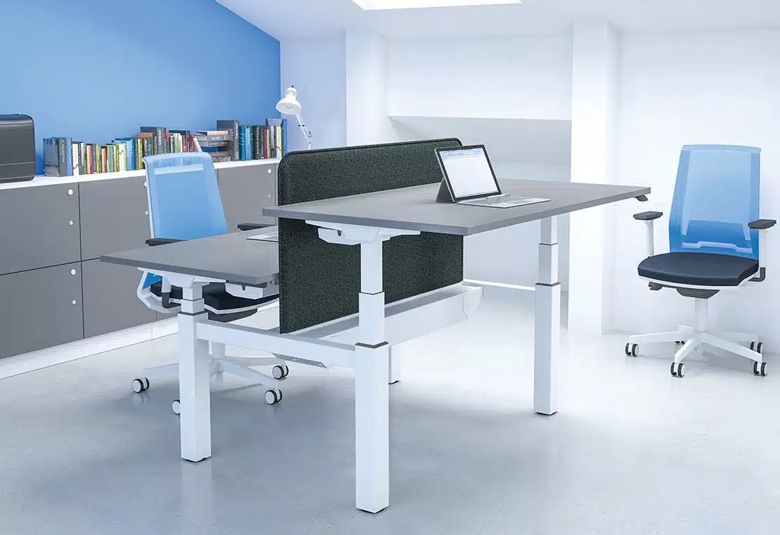 Freedom X Sit Stand back to back electric desk with white trim shown with desktops at different heights in an office