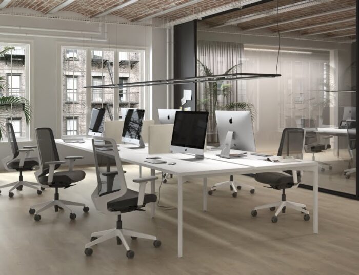 Hexa Table six person bench desk with white tops and frame shown in a workspace