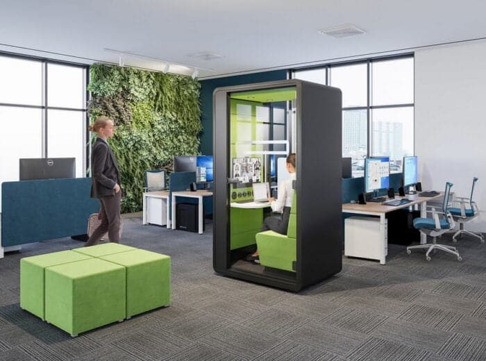 HushHybrid Pod shown in an office by a desk and four upholstered cube stools