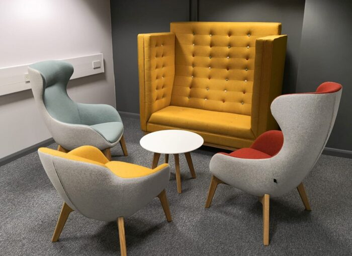 Ilk Soft Seating two high back and one low back 4 leg chair shown with a Jig high back sofa and a coffee table in a breakout space