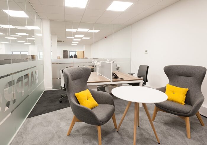Ilk Soft Seating two high back chairs with loose cushions by a round meeting table in an open plan office space