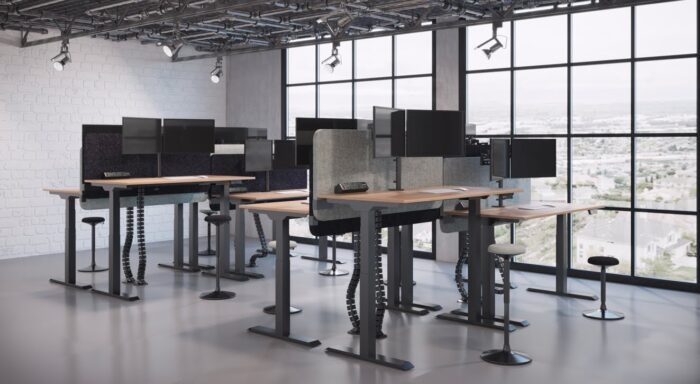 Kardo Monitor Arm dual screen arms shown mounted to a bank of sit stand desks with Sway Stools