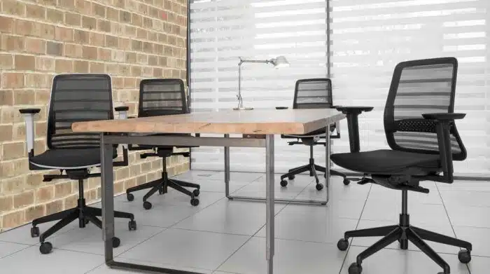 Koplus Tonique Task Chair 4 all black chairs by a table in a work space