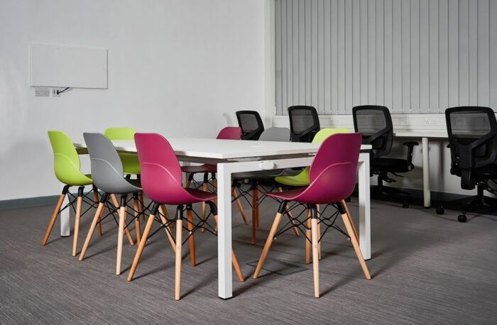 LG4 Wood Seating 8 chairs in pink, green and grey shown around a bench desk in an office space