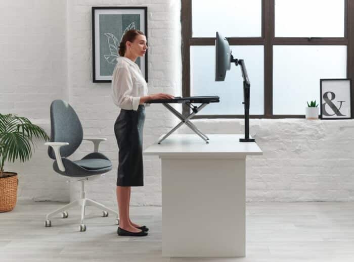 Monto Sit Stand Riser shown being used in a raised position on a fixed height office desk