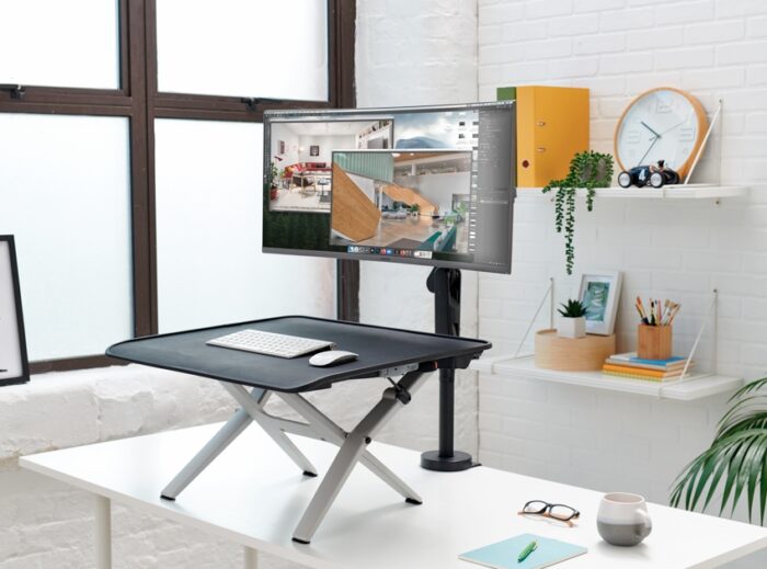 Monto Sit Stand Riser shown in a raised position with a monitor mounted on the edge of a fixed height office desk