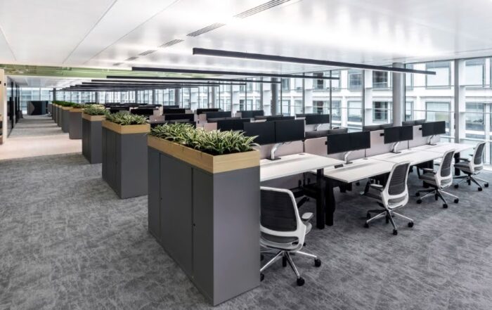 Move3 Height Adjustable Desks - 9 banks of 8 seat back to back benches shown in White with Nero Mesh chairs and end of run storage cabinets and planters.