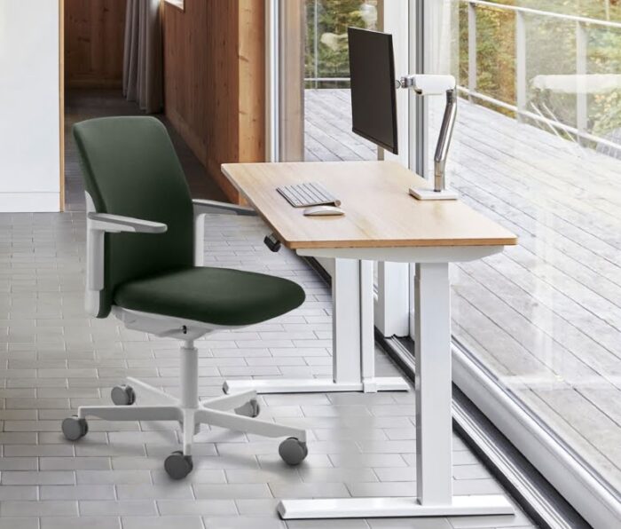 Path Task Chair with white arms and base shown by a desk in an office space