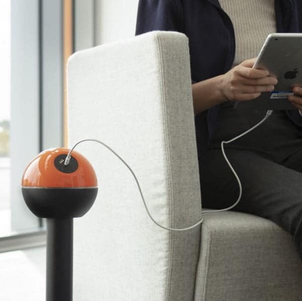 Pelican Power Module in orange and black shown next to a user who has an iPad conected to the USB charger