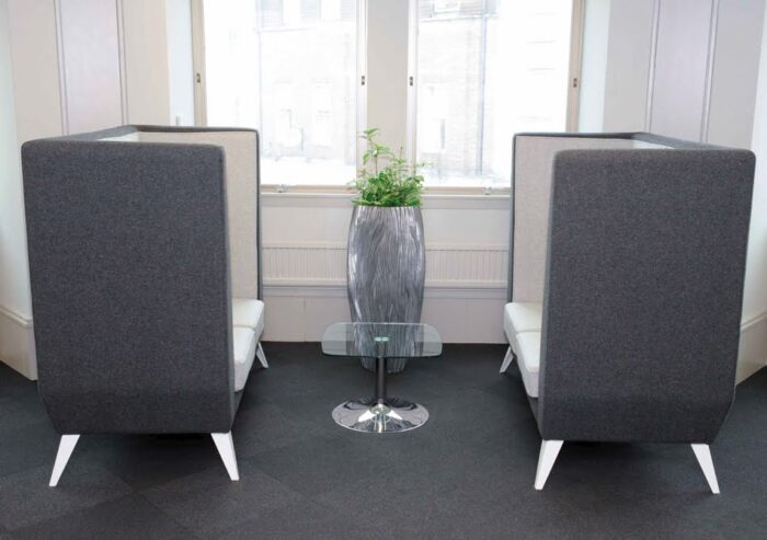 Polly Soft Seating two high back 2 seat sofas with silver legs facing each other with a small glass table in the centre