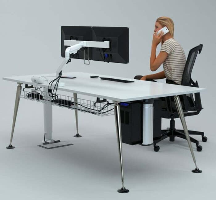 Reach Plus Monitor Arm in white shown with two screens mounted on a desk with someone working