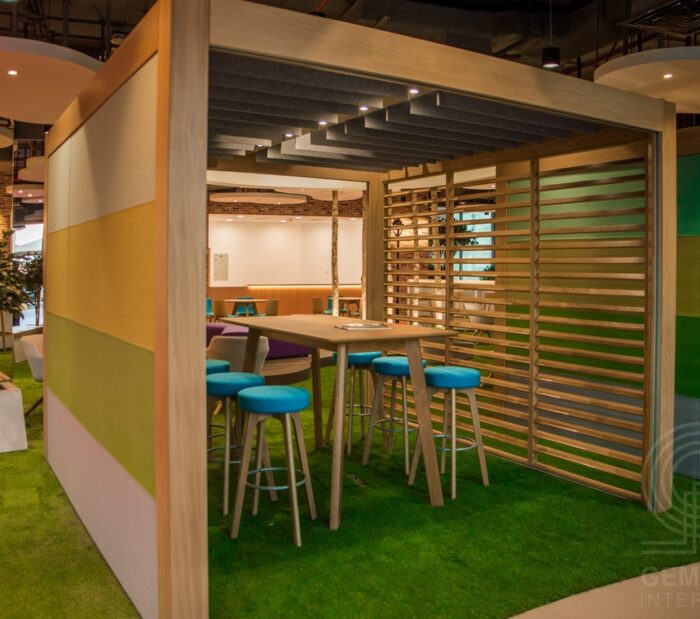 Rooms Collaboration Space with an upholstered wall and a venetian trellis wall shown with poseur table and seating in a breakout area