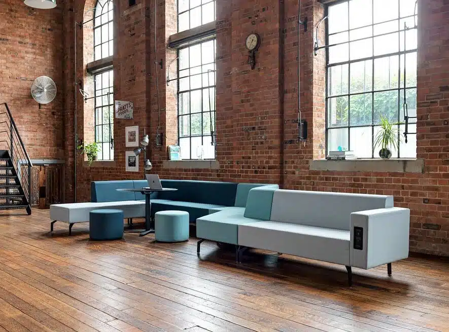 Skyline Seating with two tone upholstery and integrated power module shown with a laptop table and a couple of pouffes
