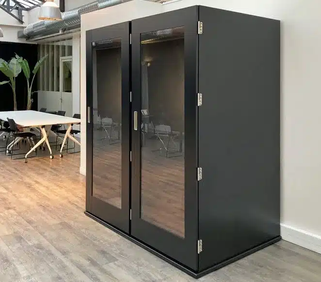 Soho Work Station - two booths side by side finished in black, shown against a wall in an open plan office space