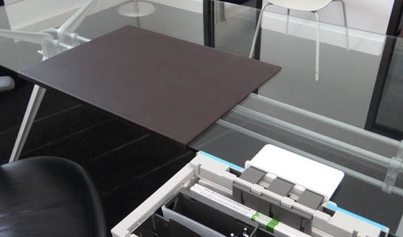 Desk Mat with smooth PU surface In brown, shown on a glass top desk