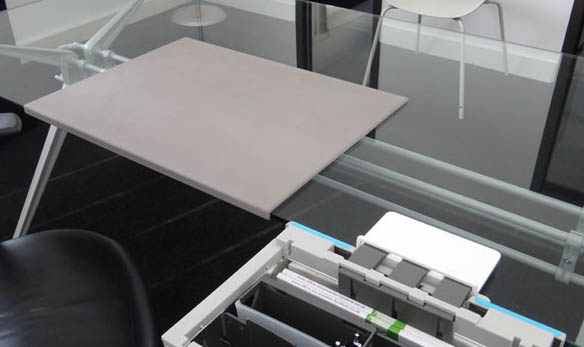 Desk Mat with padded surface In grey, shown on a glass top desk